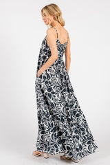 woman wearing a navy blue and white floral maxi dress with adjustable straps and side pockets