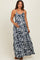 woman wearing a navy and white floral print maternity maxi dress with adjustable straps and a cinched waist, holding her baby bump