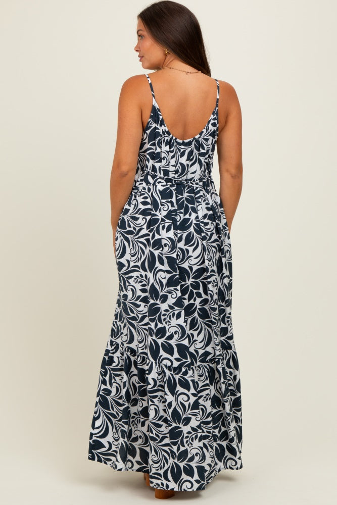 woman wearing a navy blue and white floral maternity maxi dress with a low back and spaghetti straps