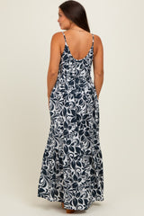 woman wearing a navy blue and white floral maternity maxi dress with a low back and spaghetti straps