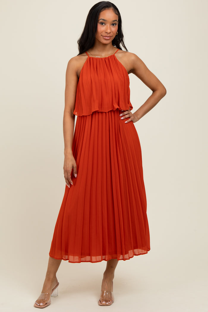 woman wearing an orange pleated midi dress with a halter neck and layered bust detailing