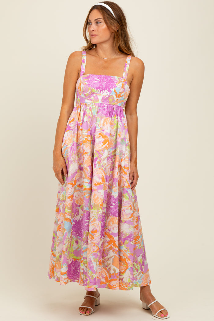 woman wearing a floral maxi dress in pink, orange, and lavender with a square neckline and spaghetti straps