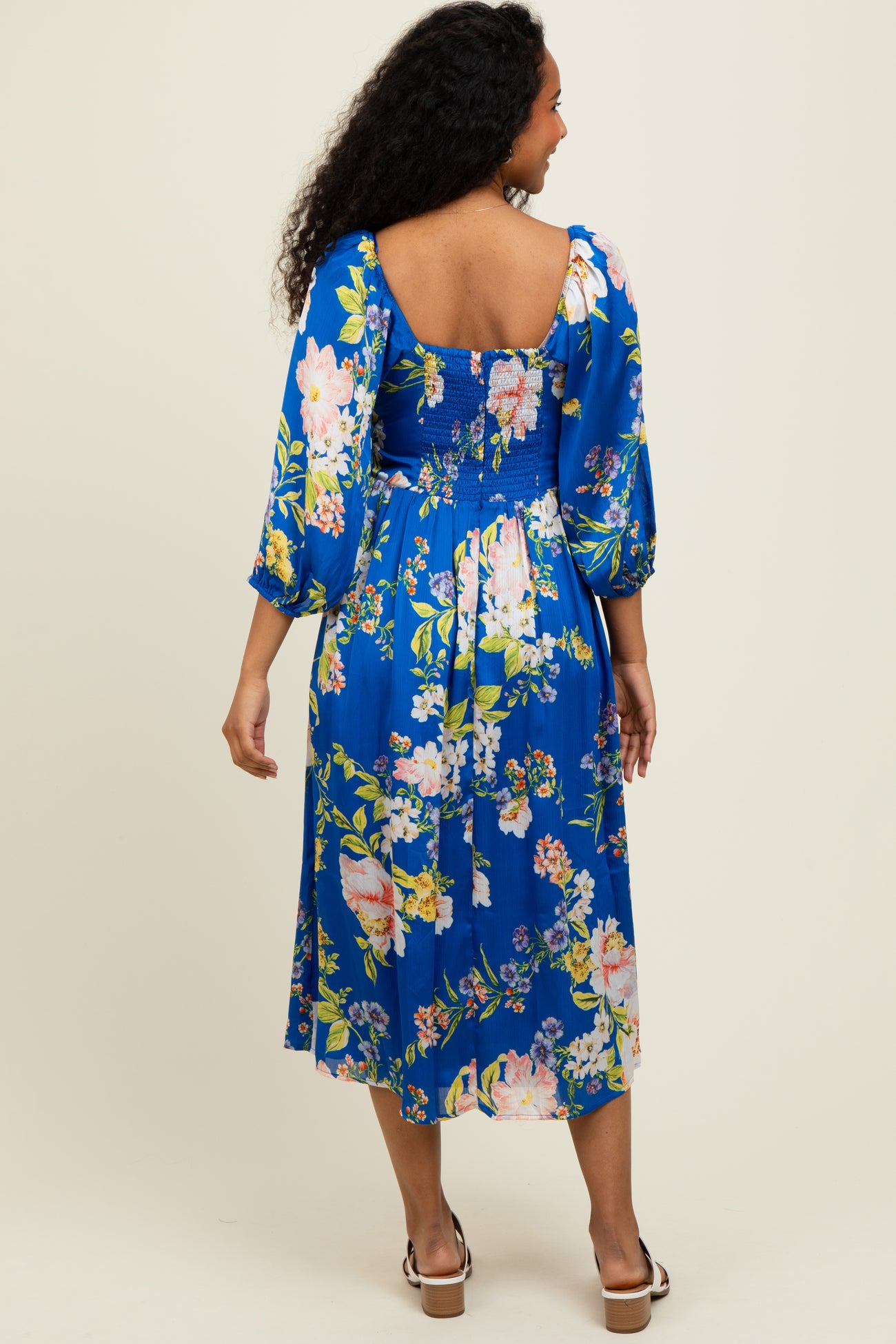 woman wearing a blue floral midi dress with long sleeves and a smocked back detail