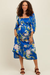 woman wearing a blue floral maternity dress with puff sleeves and a visible baby bump