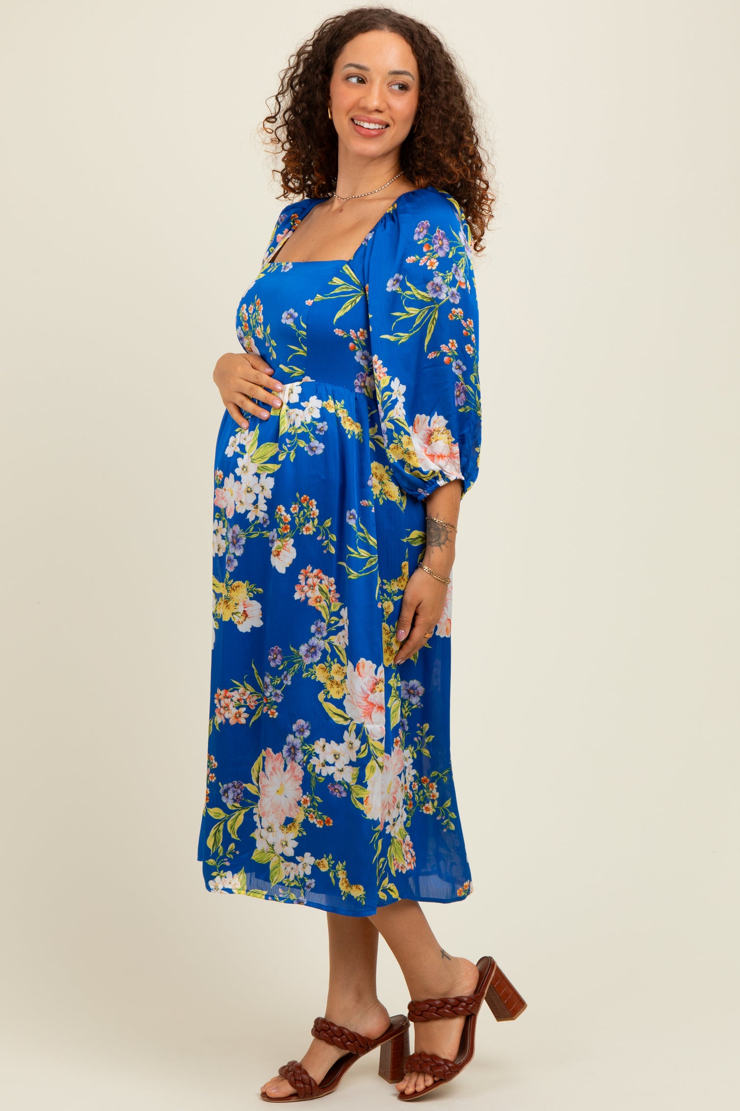 woman wearing a floral blue maternity dress with 3/4 sleeves and a visible baby bump