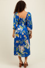 woman wearing a blue floral maternity dress with puff sleeves and a fitted bodice, showcasing a flowing skirt