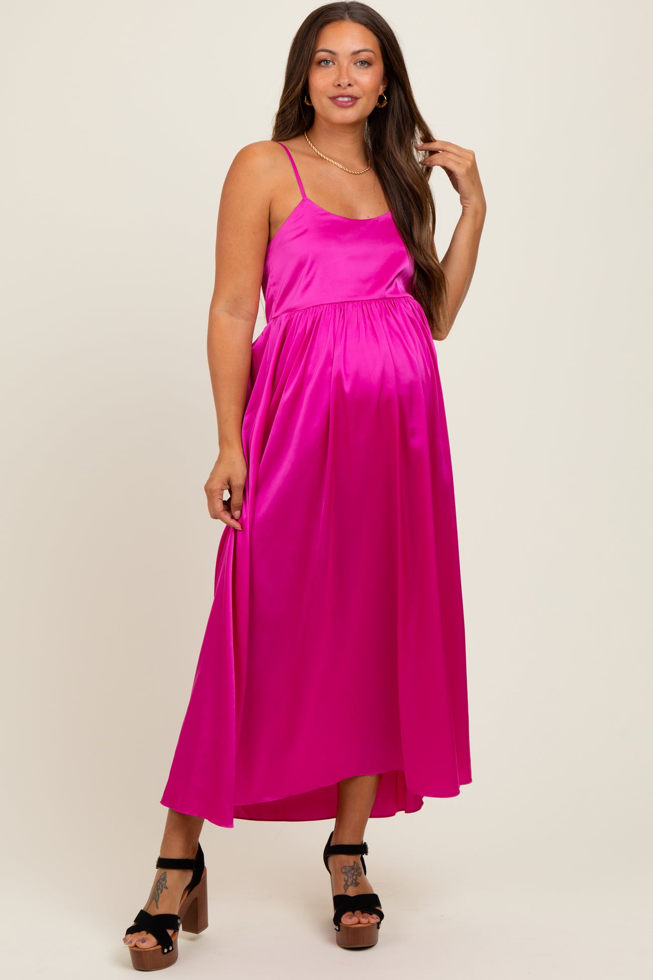 woman wearing a bright pink maternity maxi dress with spaghetti straps and a flowy silhouette, showcasing her baby bump