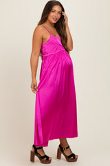 woman wearing a bright pink satin maternity maxi dress with adjustable straps and a flowing silhouette, showing her baby bump