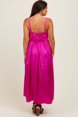woman wearing a bright pink maternity maxi dress with a tied back detail and adjustable straps