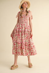 woman wearing a floral print maxi dress with tiered ruffles and bow straps, styled with a straw hat and sandals