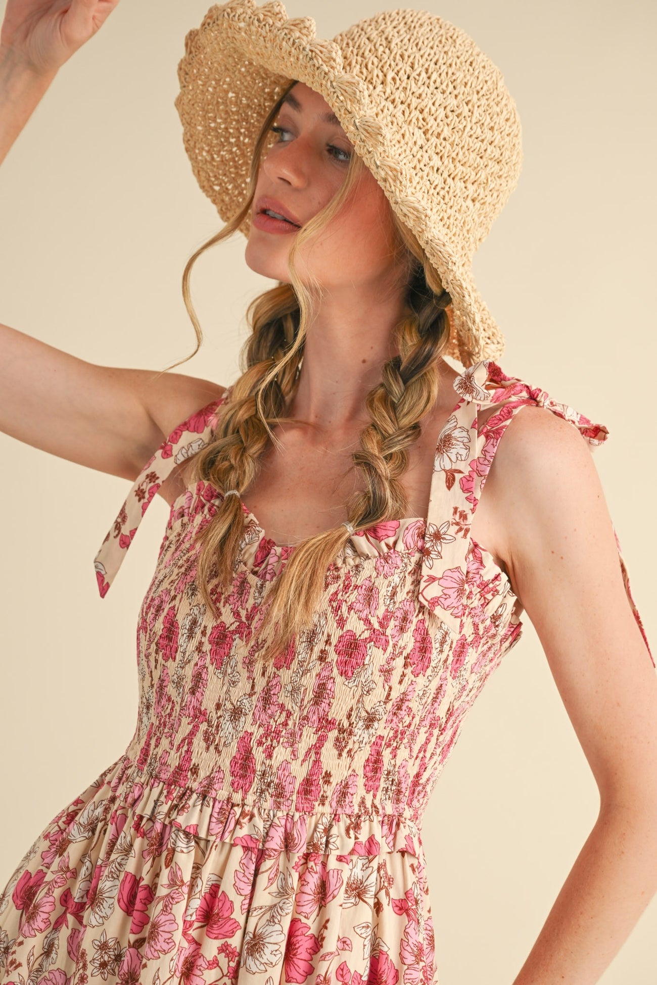 woman wearing a floral smocked sundress with tie straps and a straw sun hat