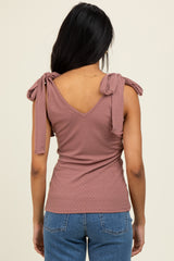 woman wearing a mauve ribbed top with v-neck and tie shoulder details, seen from the back