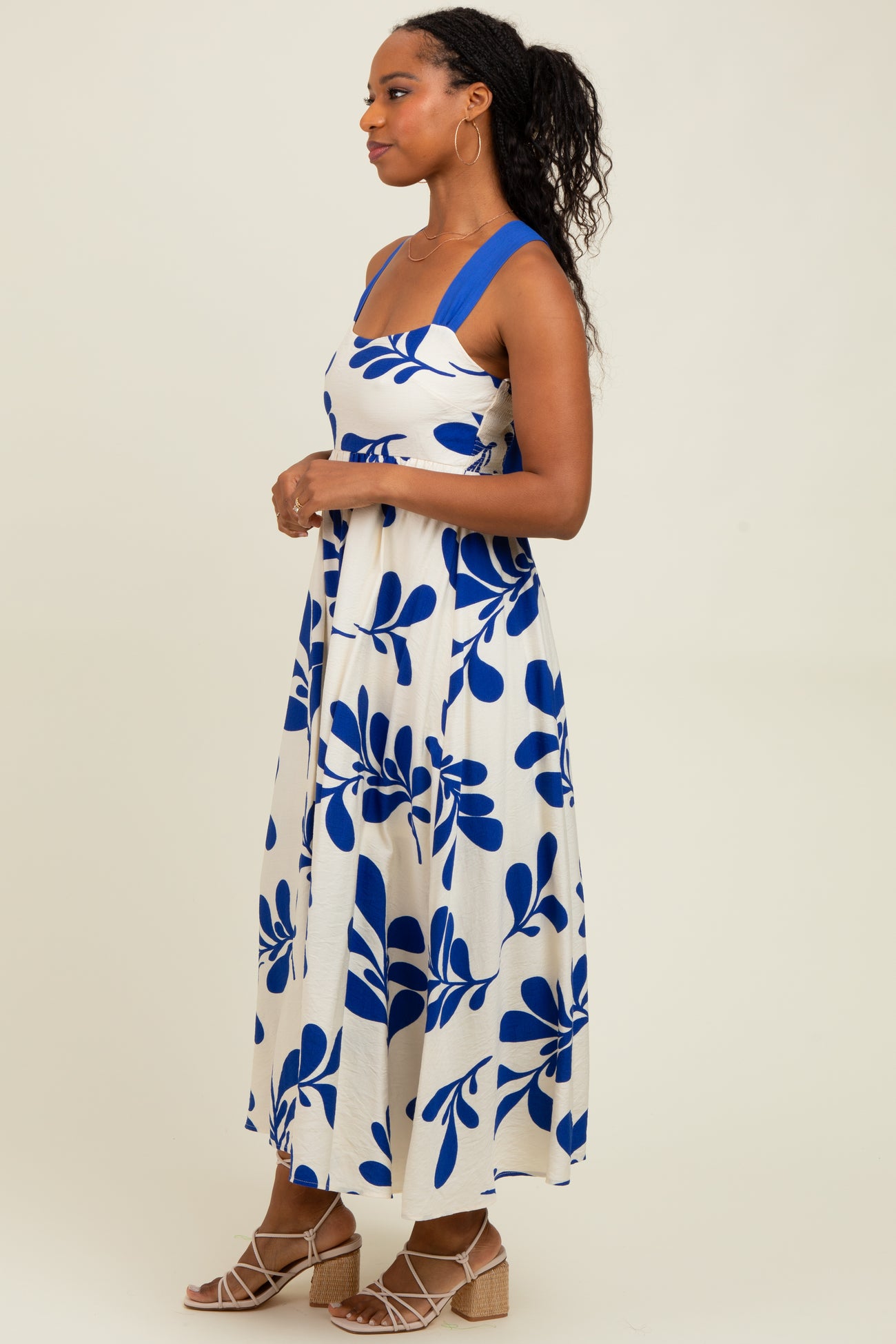 woman wearing a white maxi dress with blue leaf prints and wide straps, styled with wedge sandals