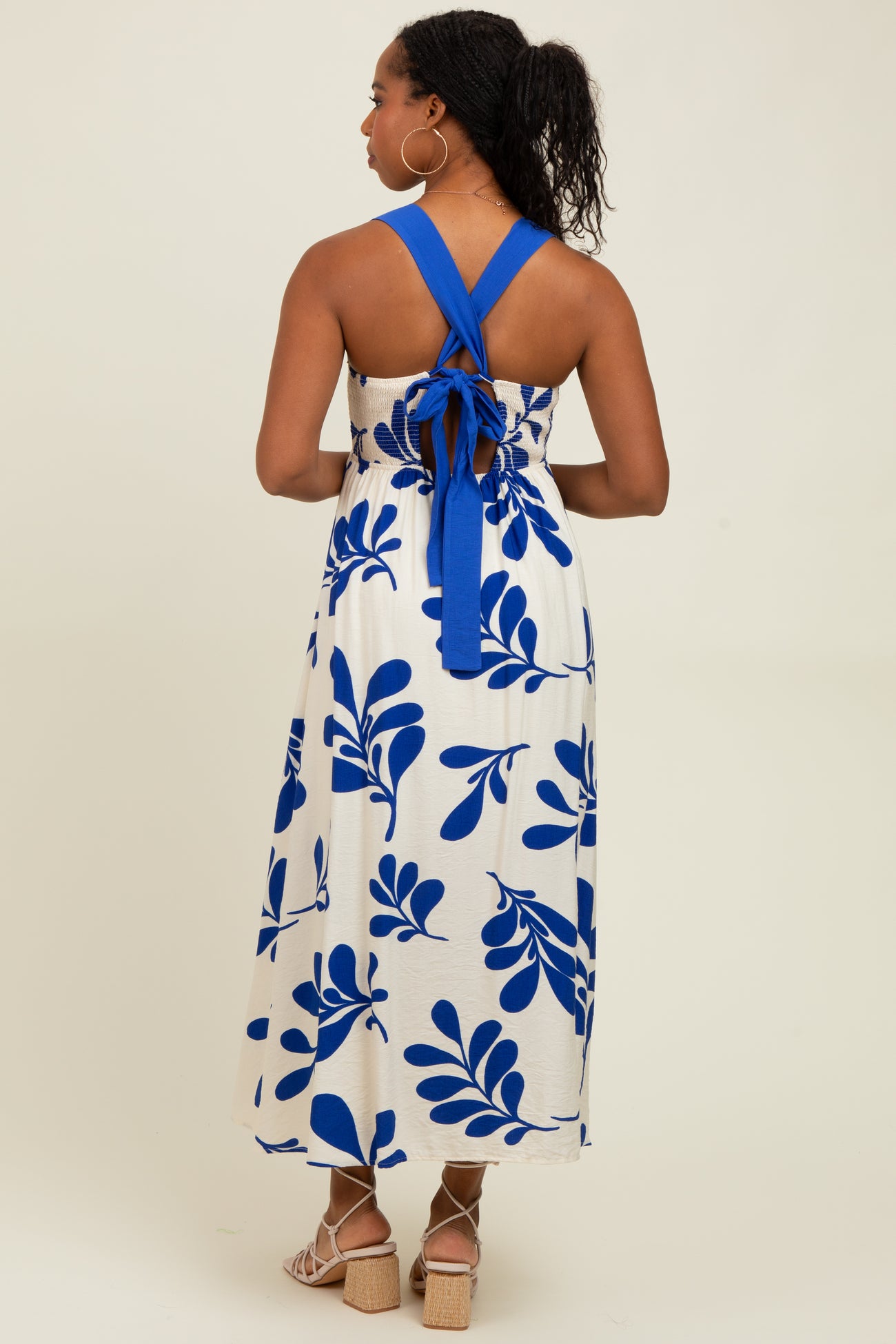 woman wearing a white and blue floral print maxi dress with a halter neck and open back design