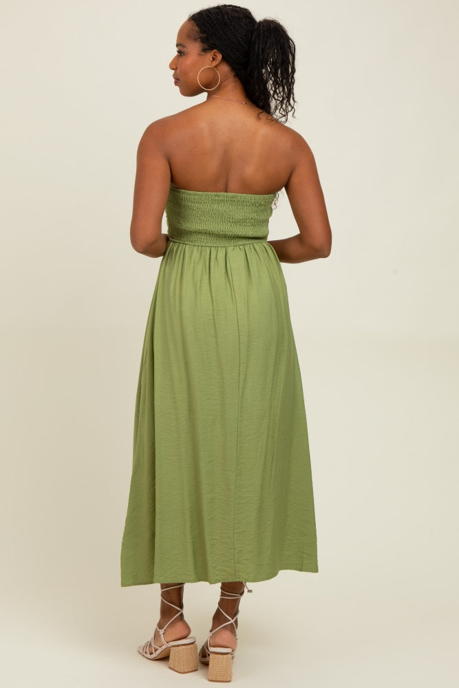 woman wearing a back view of a green strapless maxi dress with a smocked bodice and flowing skirt