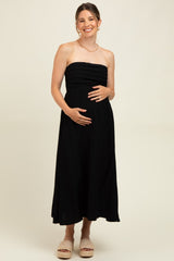 woman wearing a black strapless maternity dress and gently cradling her baby bump