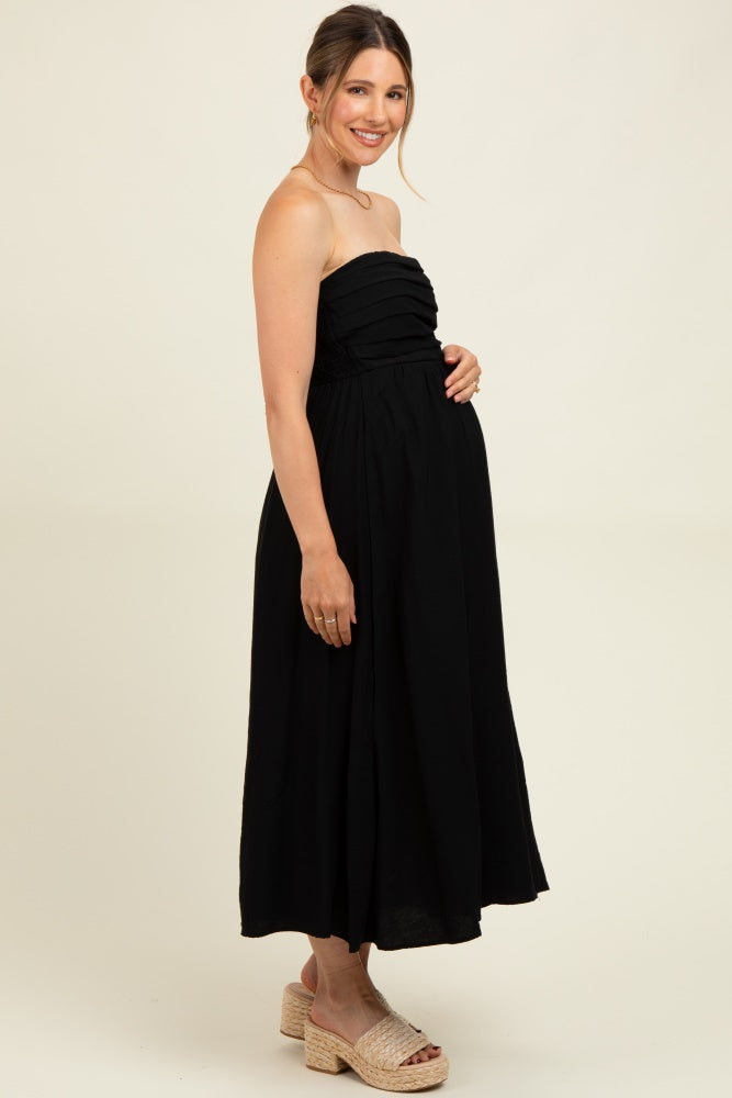 woman wearing a black strapless maternity dress with gathered detailing and a visible baby bump