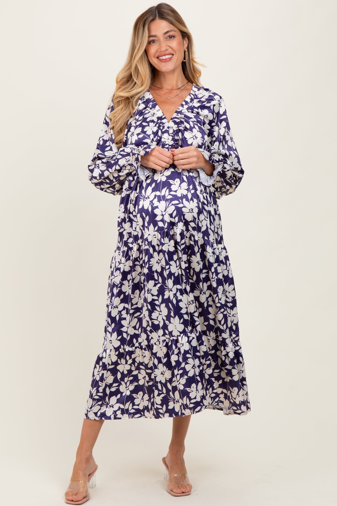 woman wearing a navy floral maternity dress with a v-neckline and long sleeves, showing her baby bump