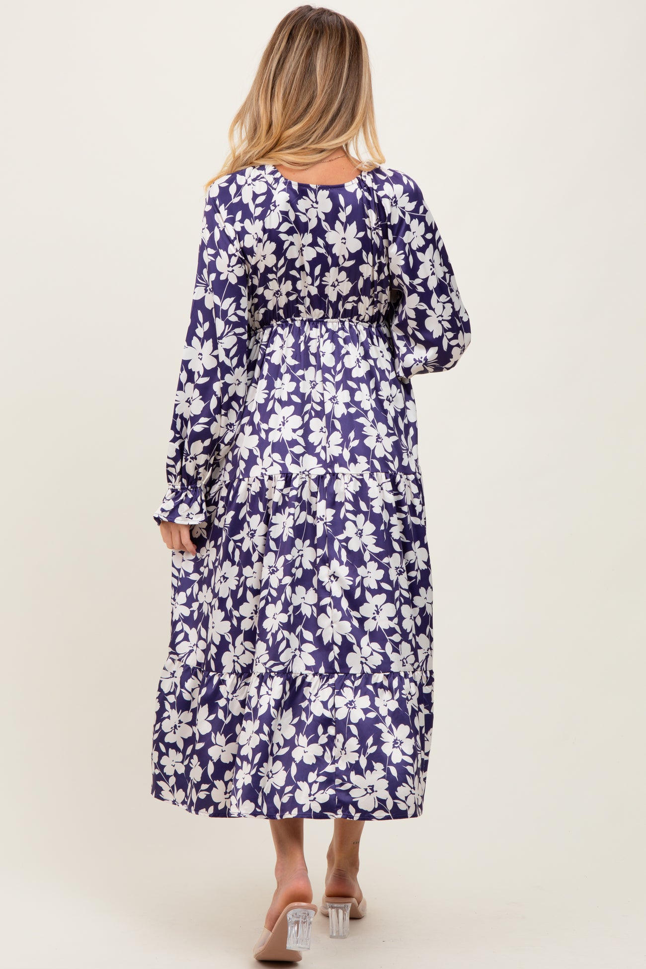 woman wearing a floral print purple maternity maxi dress, showing the back view with long sleeves and flowing skirt