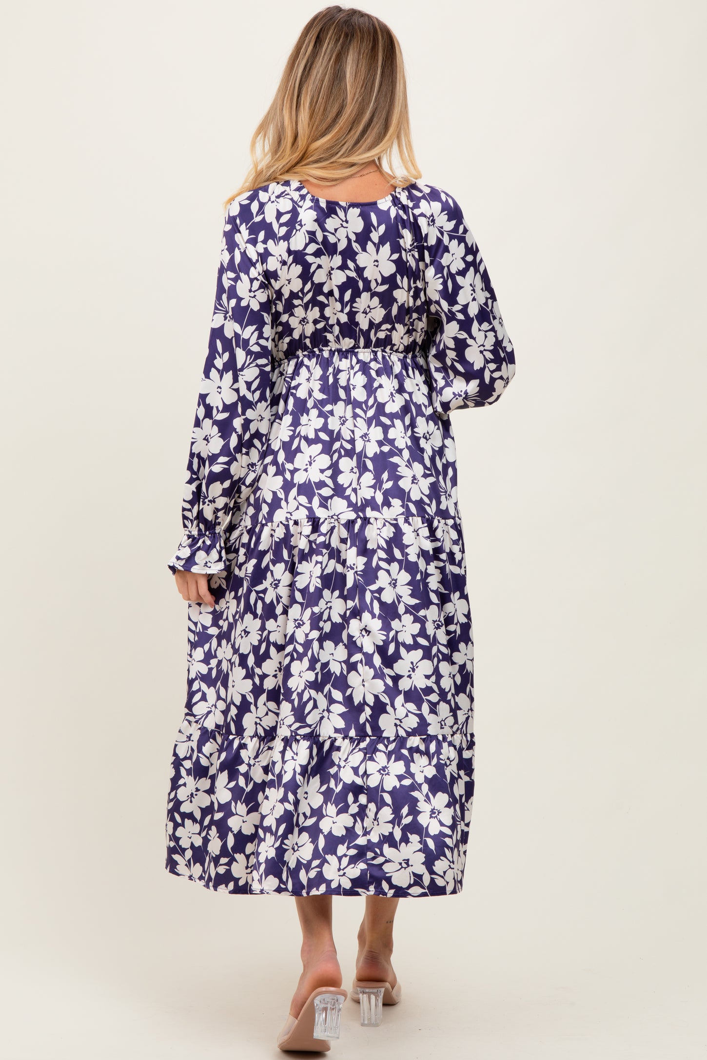 woman wearing a floral print purple maternity maxi dress, showing the back view with long sleeves and flowing skirt