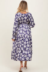 woman wearing a floral print purple maternity maxi dress, showing the back view with long sleeves and flowing skirt