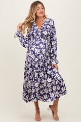 woman wearing a purple floral maternity dress with long sleeves and a flowy skirt, showcasing her baby bump