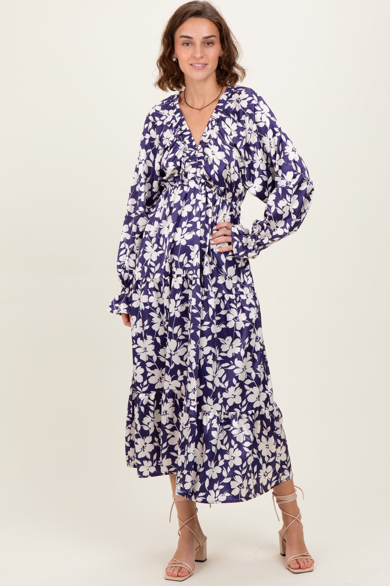 woman wearing a purple floral long sleeve maxi dress with a cinched waist and ruffled hem
