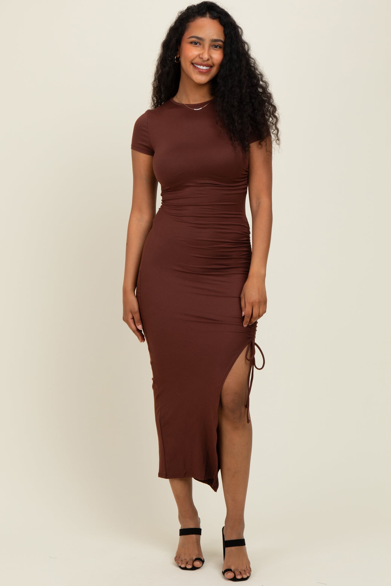 woman wearing a brown bodycon dress with short sleeves and a side slit, styled with black strappy heels