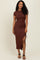 woman wearing a brown bodycon dress with short sleeves and a side slit, styled with black strappy heels