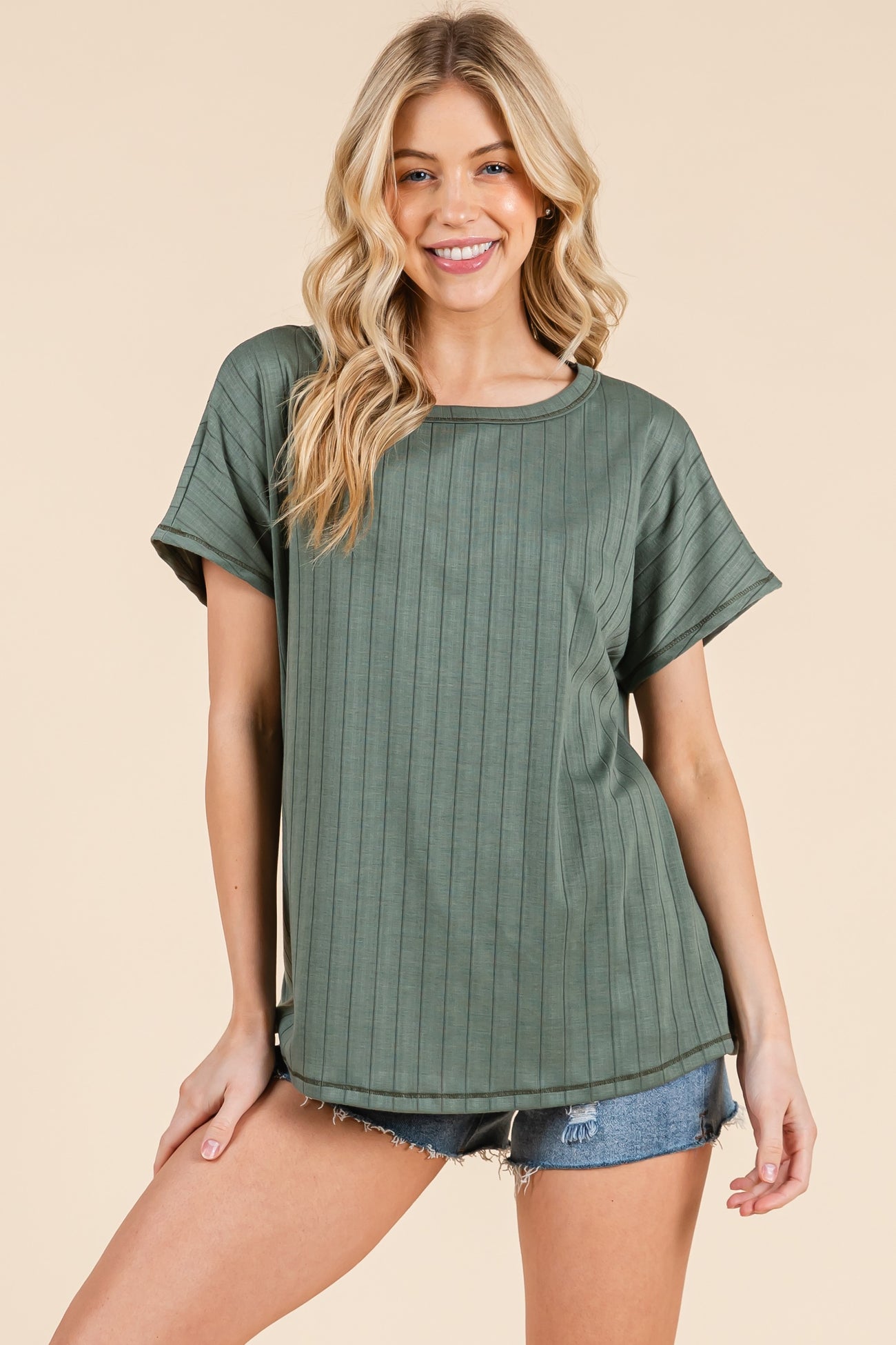 woman wearing a green ribbed short sleeve top with a relaxed fit and styled with denim shorts