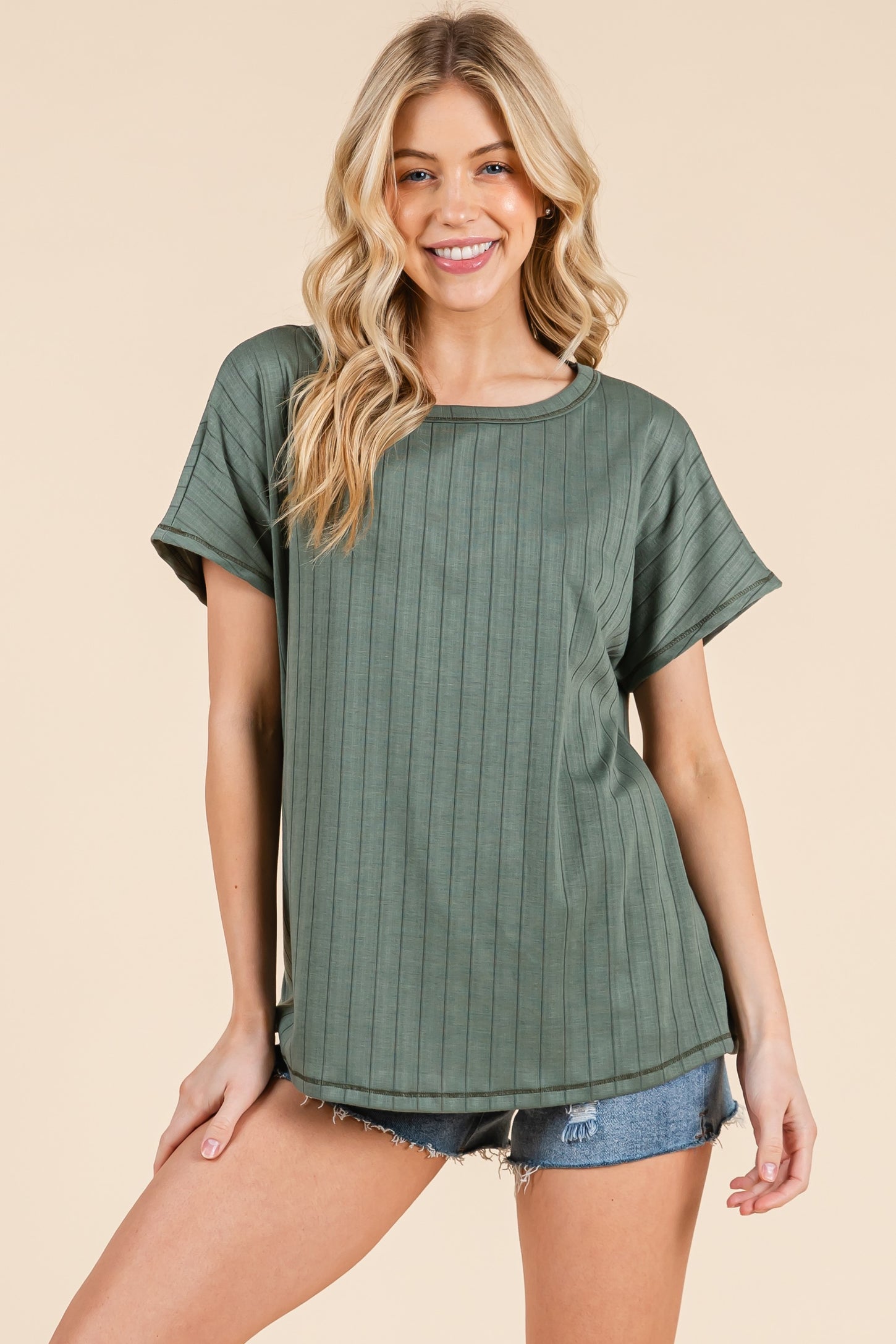 woman wearing a green ribbed short sleeve top with a relaxed fit and styled with denim shorts