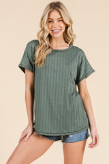 woman wearing a green ribbed short sleeve top with a relaxed fit and styled with denim shorts