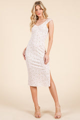 woman wearing a light pink floral midi dress with a fitted silhouette and side slit