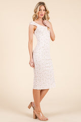 woman wearing a fitted white floral midi dress with off-shoulder straps and tan block heel sandals