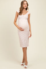 woman wearing a pink floral maternity dress that hugs her baby bump