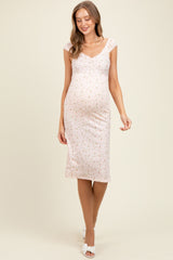 woman wearing a pink floral maternity dress with cap sleeves and a visible baby bump