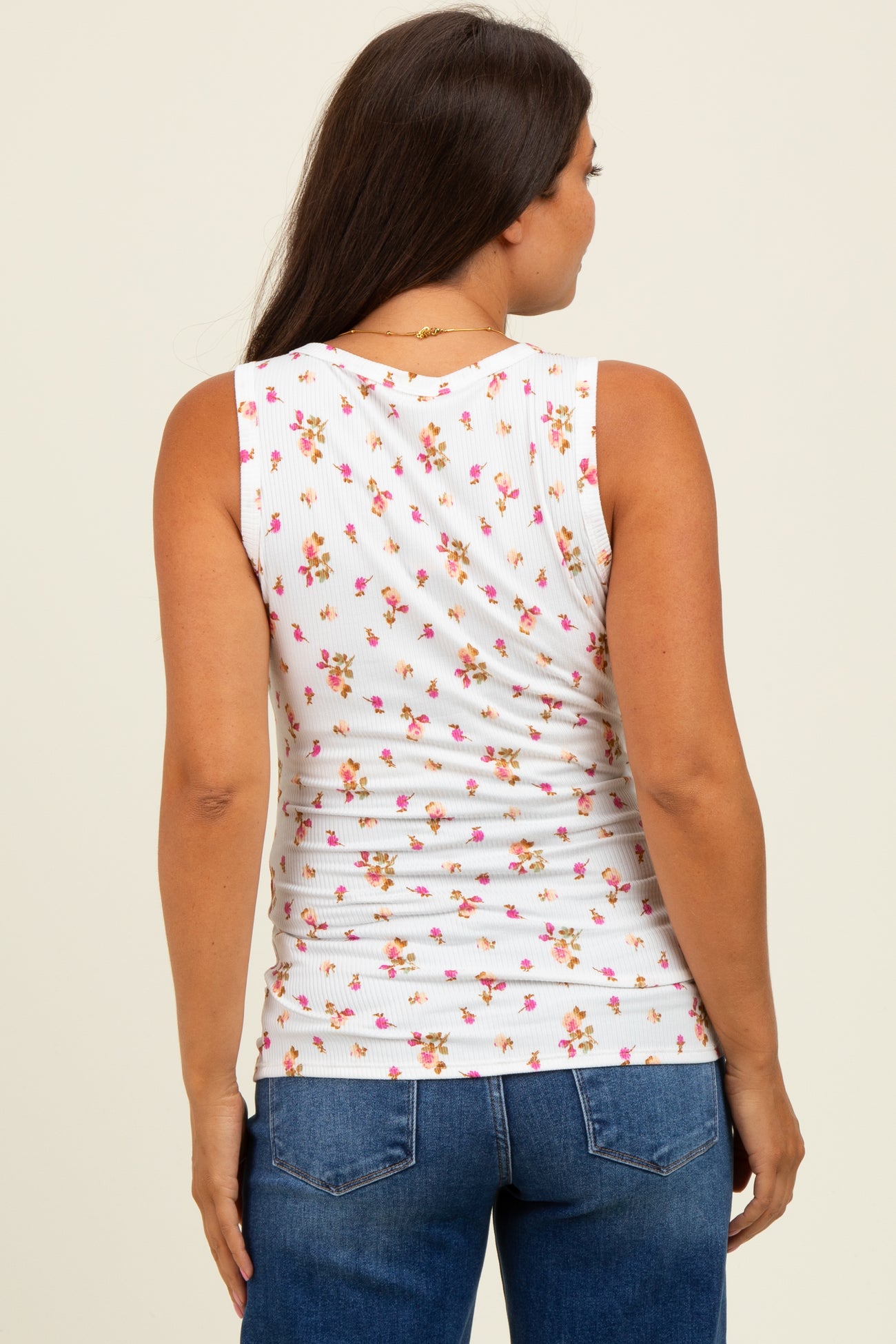 woman wearing a white sleeveless maternity top with a floral print and a fitted style, from the back