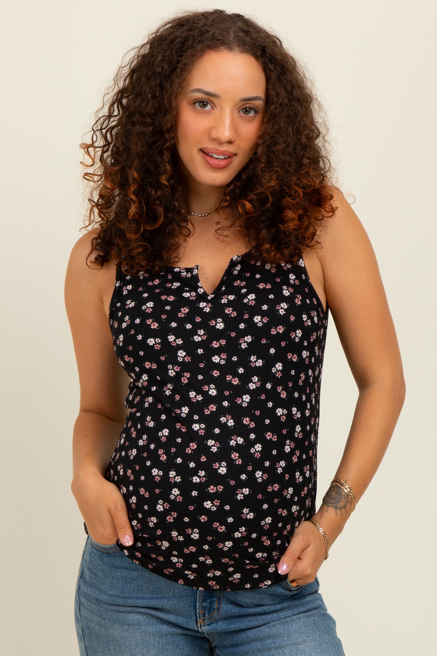 woman wearing a black floral maternity tank top and showing her baby bump