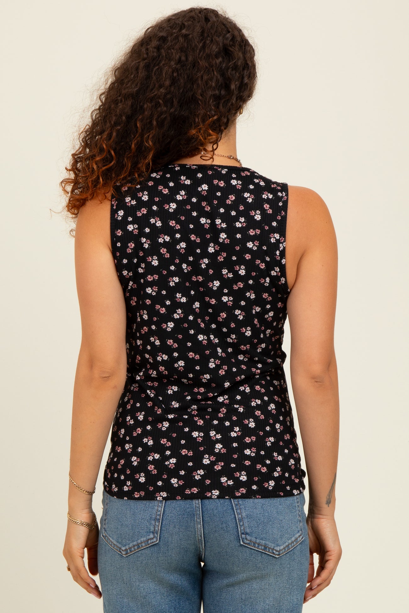 woman wearing a black floral maternity tank top with a fitted silhouette and showing her back