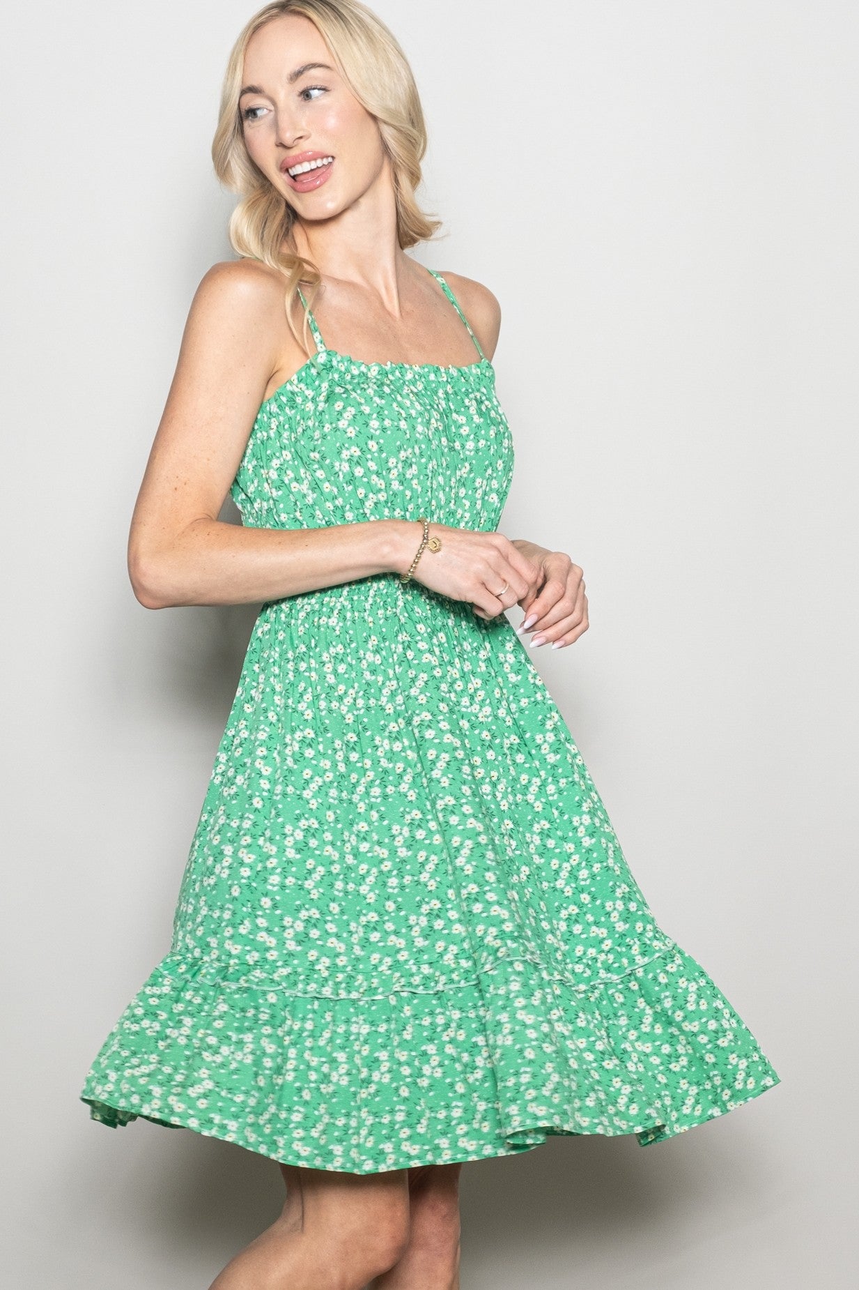 woman wearing a green floral sundress with a tiered skirt and spaghetti straps