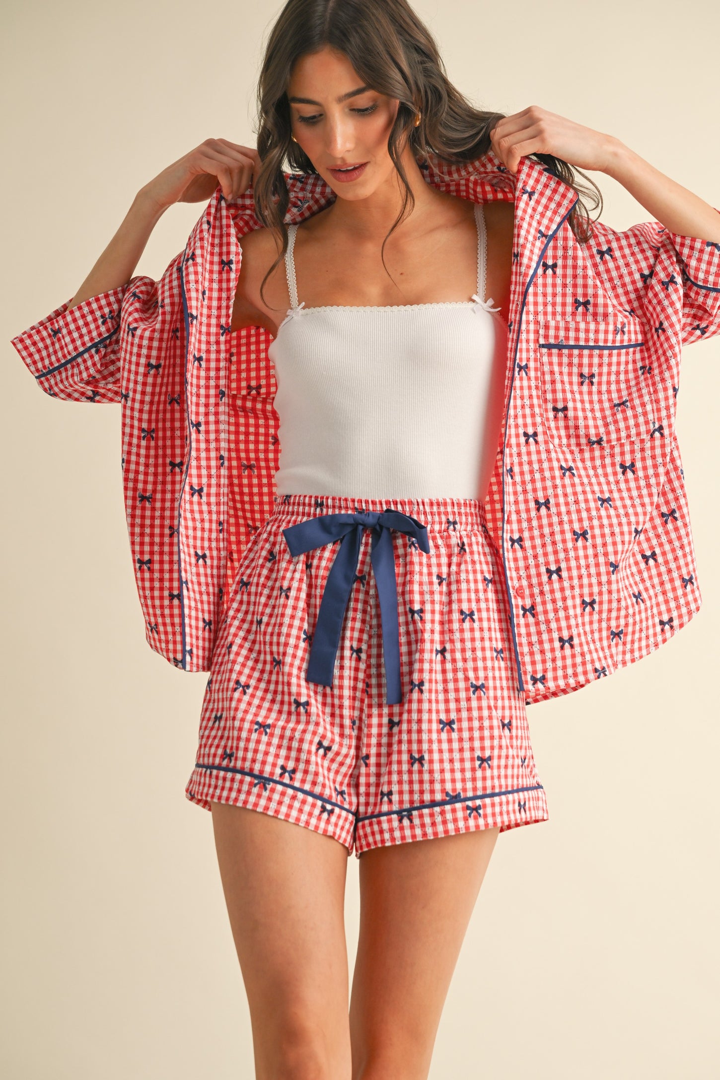 woman wearing a red and white gingham print pajama set with a short-sleeve button-up shirt and matching shorts
