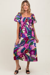 woman wearing a colorful floral maternity dress with puff sleeves and a square neckline