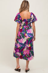 woman wearing a colorful floral print maternity dress with puff sleeves and a smocked back design