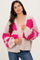 woman wearing a beige cardigan with bright pink floral patterns and puffed sleeves