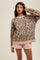 woman wearing a beige leopard print oversized sweater and pink shorts