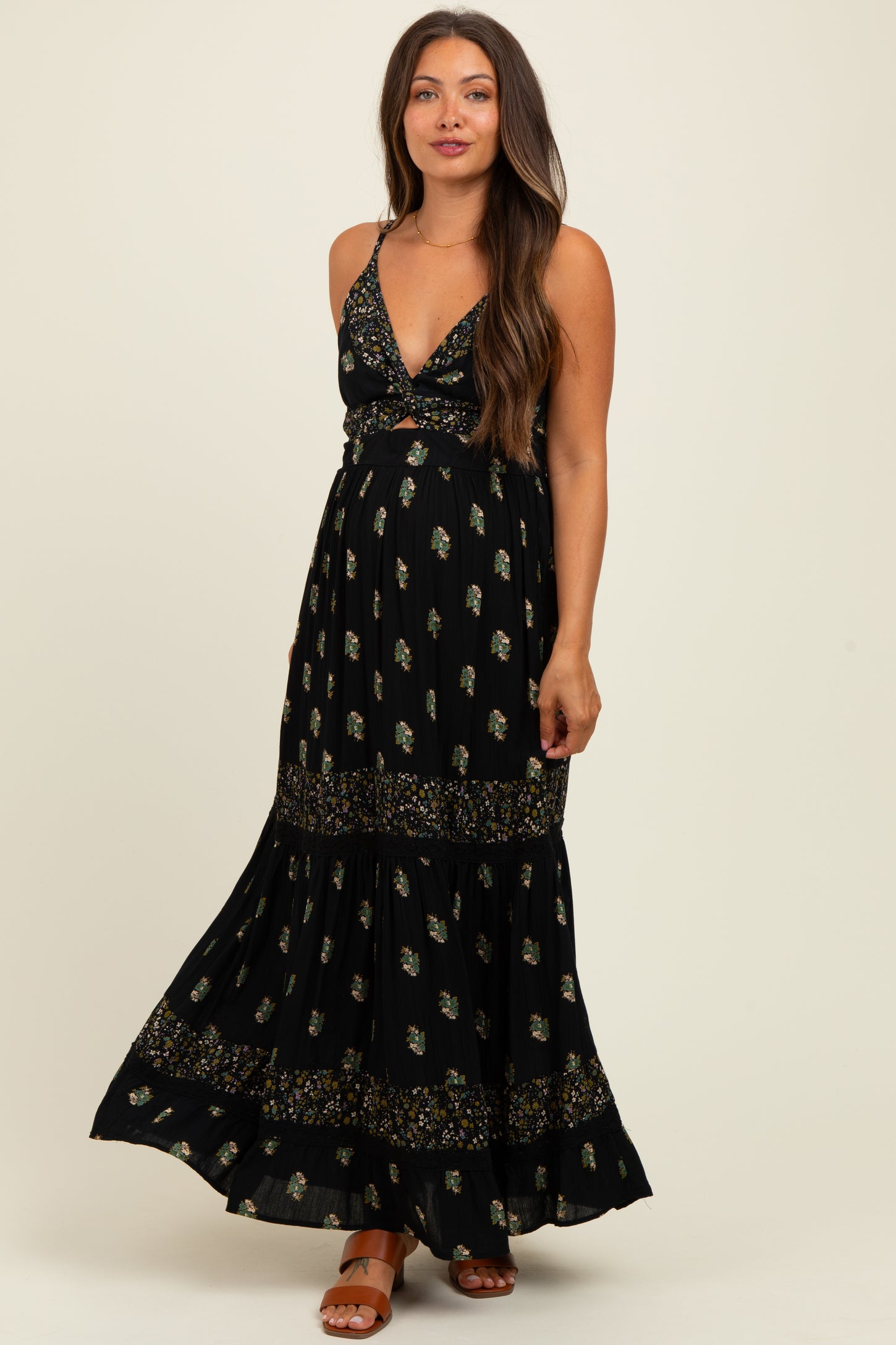 woman wearing a black floral maternity maxi dress with a plunging neckline and a flowy skirt, showing her baby bump