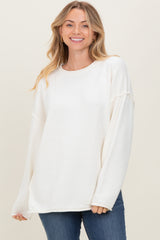 woman wearing a white oversized sweater with long sleeves and a relaxed fit, smiling at the camera