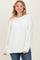 woman wearing a white oversized sweater with long sleeves and a relaxed fit, smiling at the camera