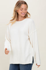 woman wearing a white long sleeve oversized sweater with side slits and a relaxed fit