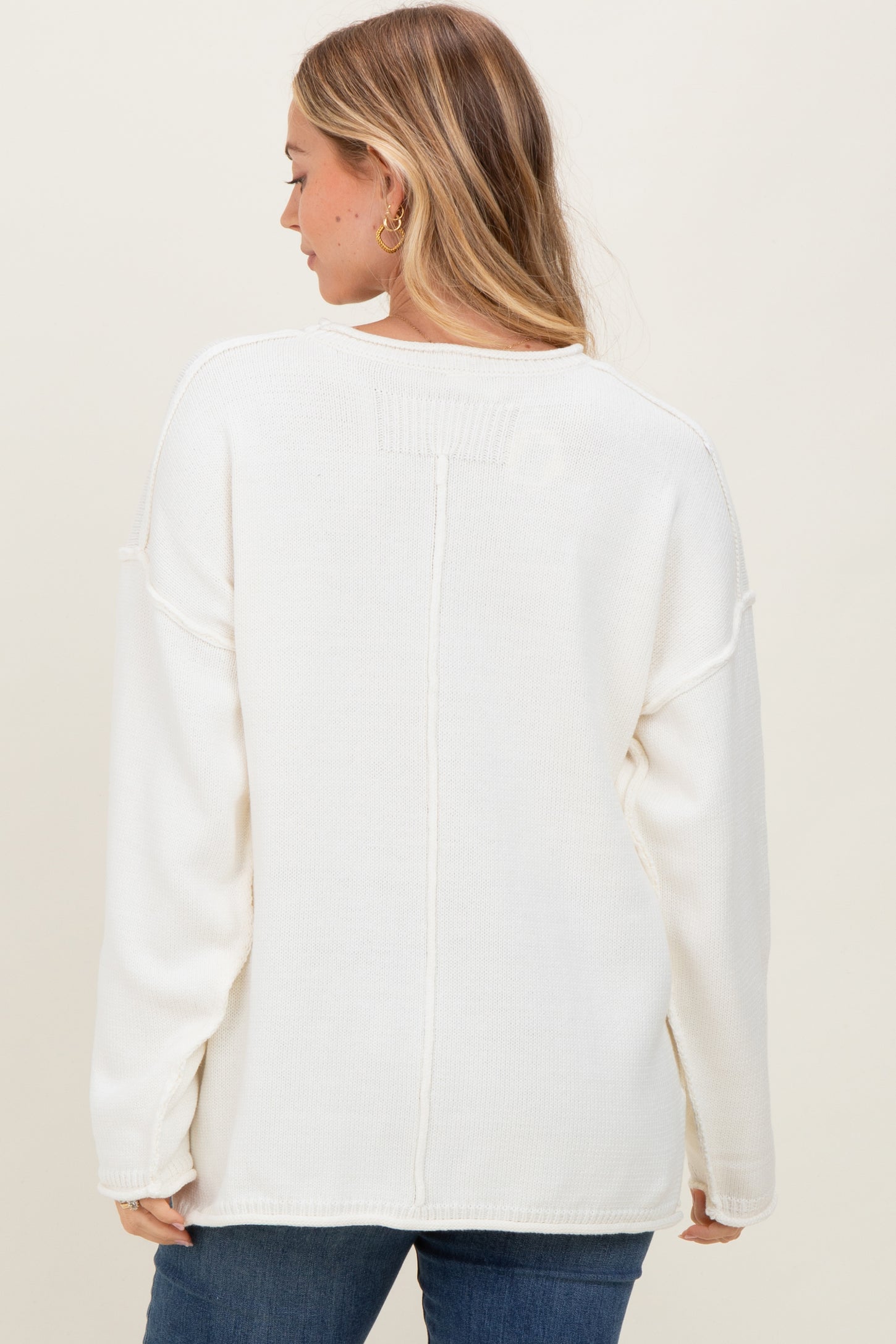 woman wearing a white oversized knit sweater with a relaxed fit and dropped shoulder seams